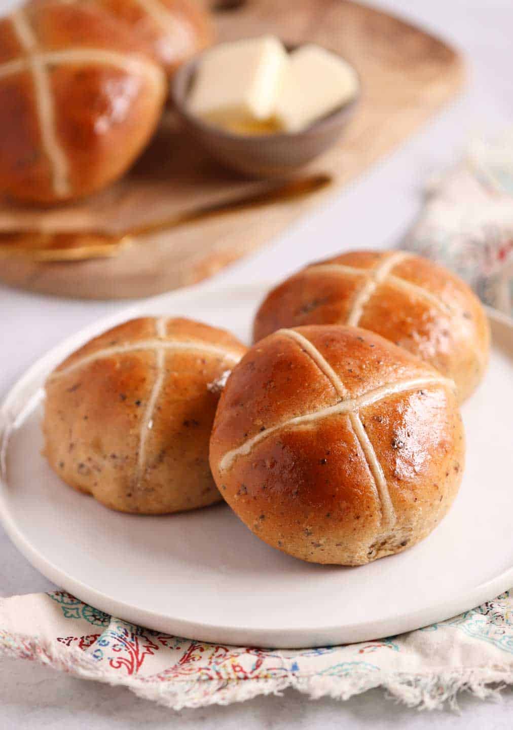 up close shot of hot cross buns on a place with some in the background