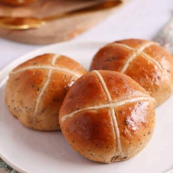 Hot cross buns with a flour cross on a white plate