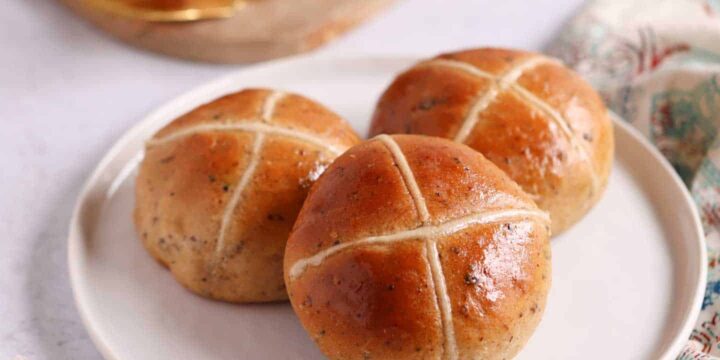Hot cross buns with a flour cross on a white plate