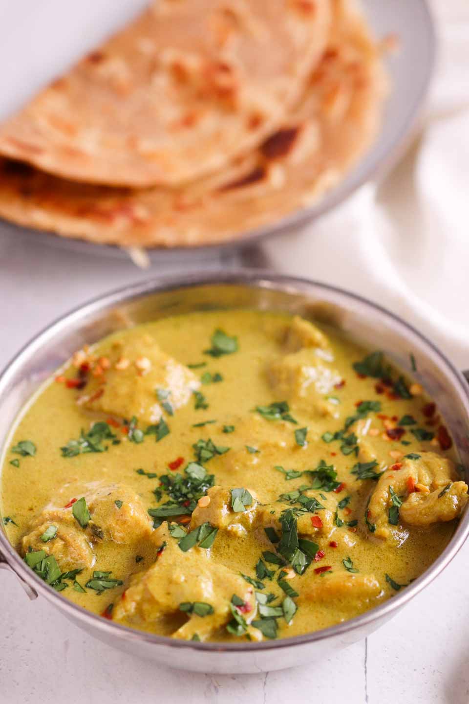 Coconut Chicken Curry served roti topped with chopped parsley and red pepper flakes. 