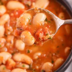 an overhead shot of butter bean stew in the background with a spoonful in the foreground.