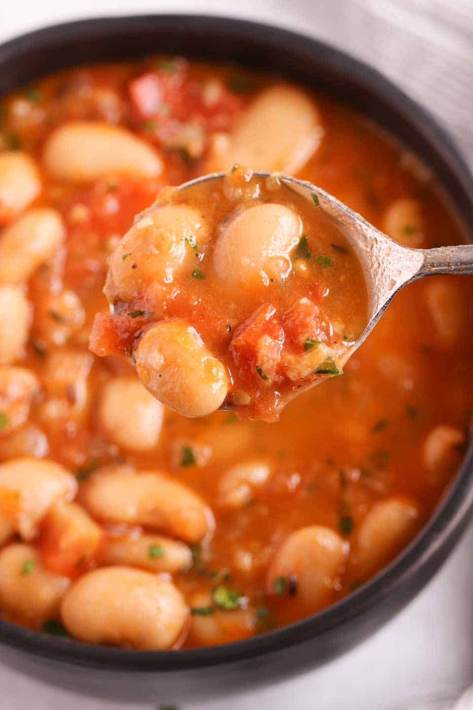 an overhead shot of butter bean stew in the background with a spoonful in the foreground.