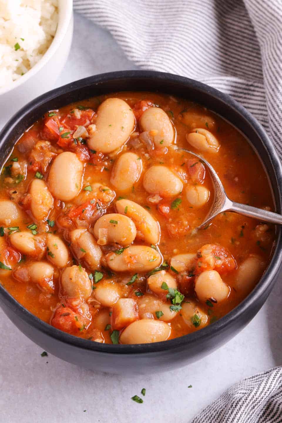 A bowl of butter bean stew with a spoon lifting some of the beans
