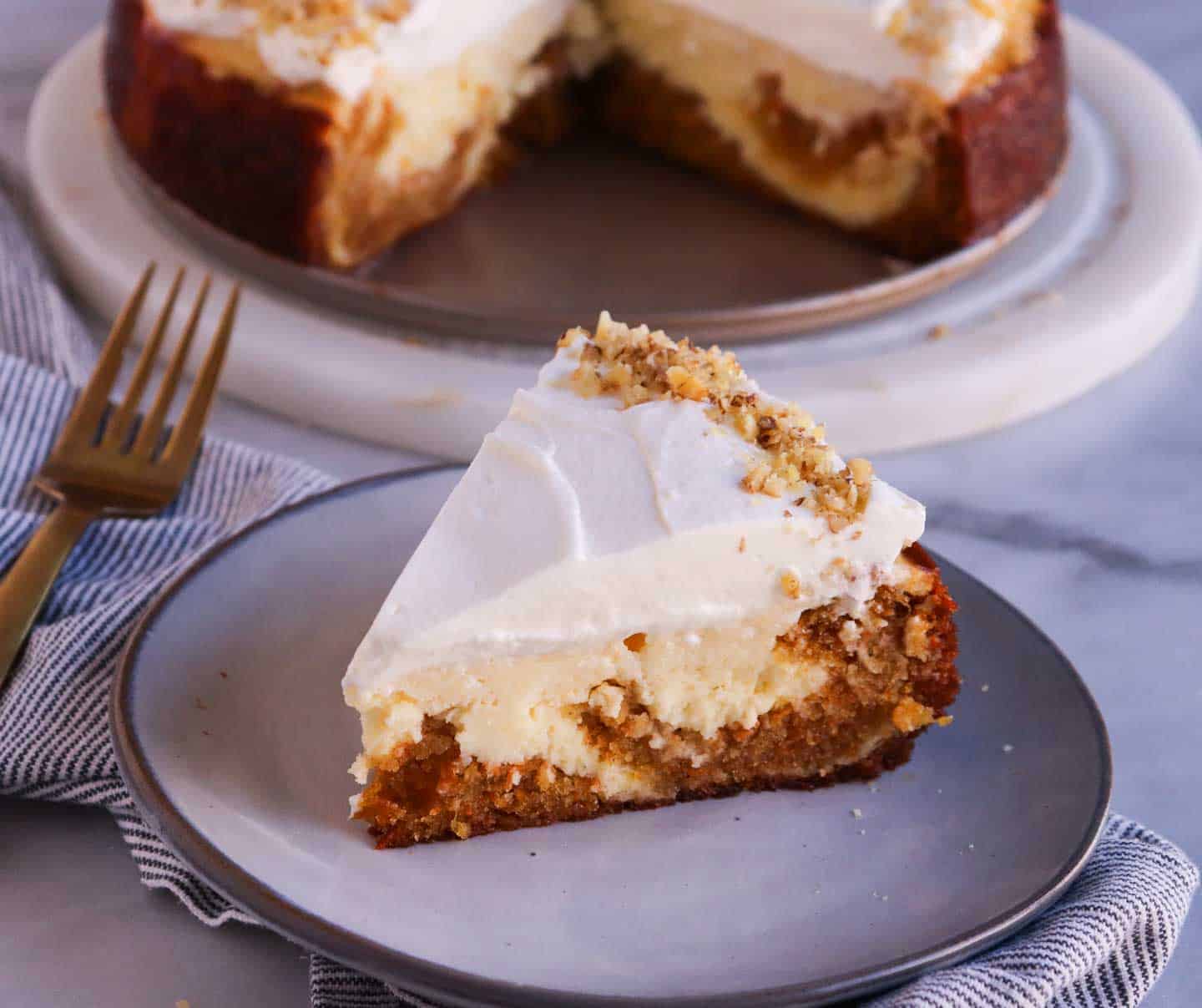 a slice of carrot cake cheesecake with a cut cake in the background