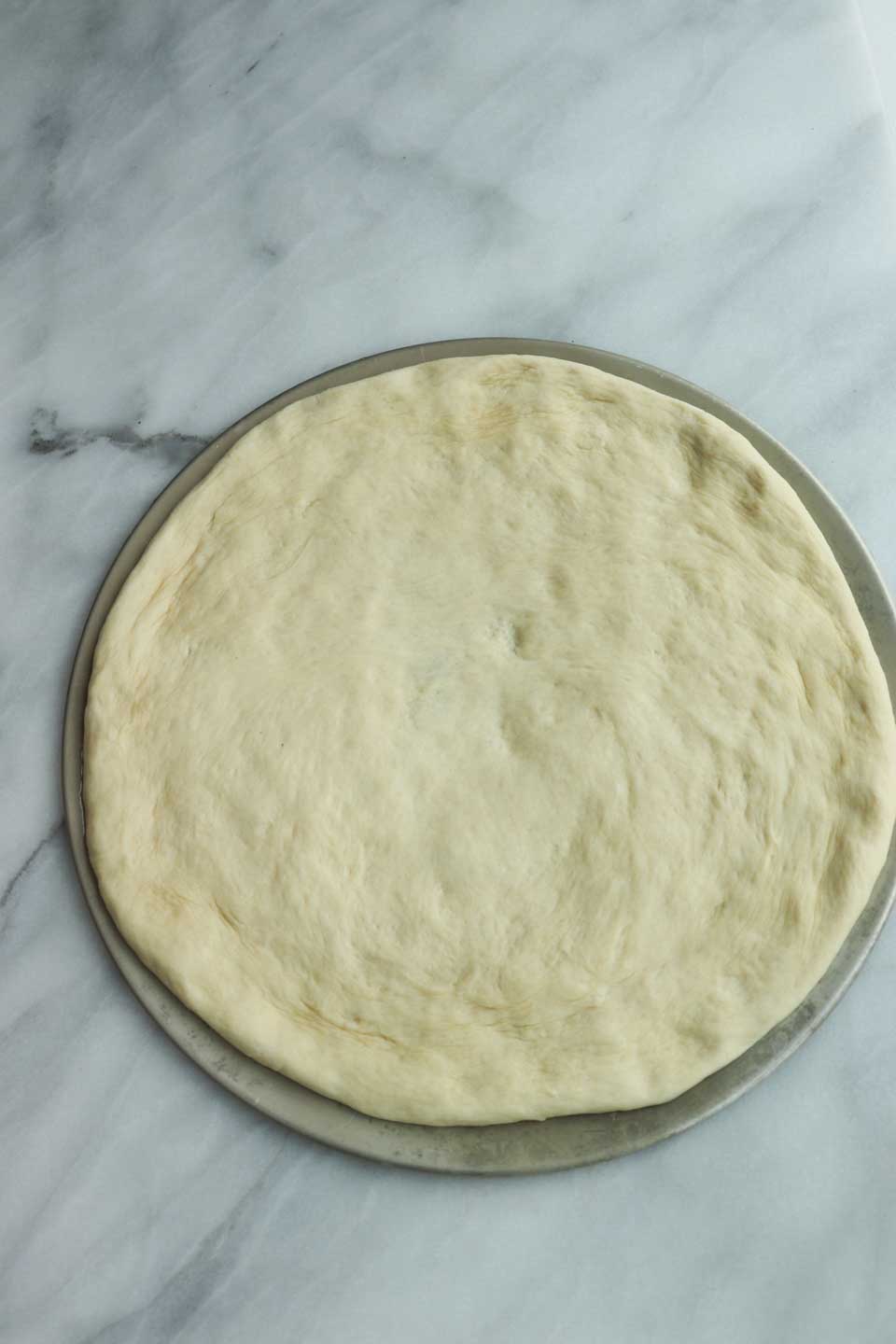 pizza dough rolled out on a round pizza pan