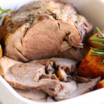 roasted lamb in a baking pan with roasted potatoes