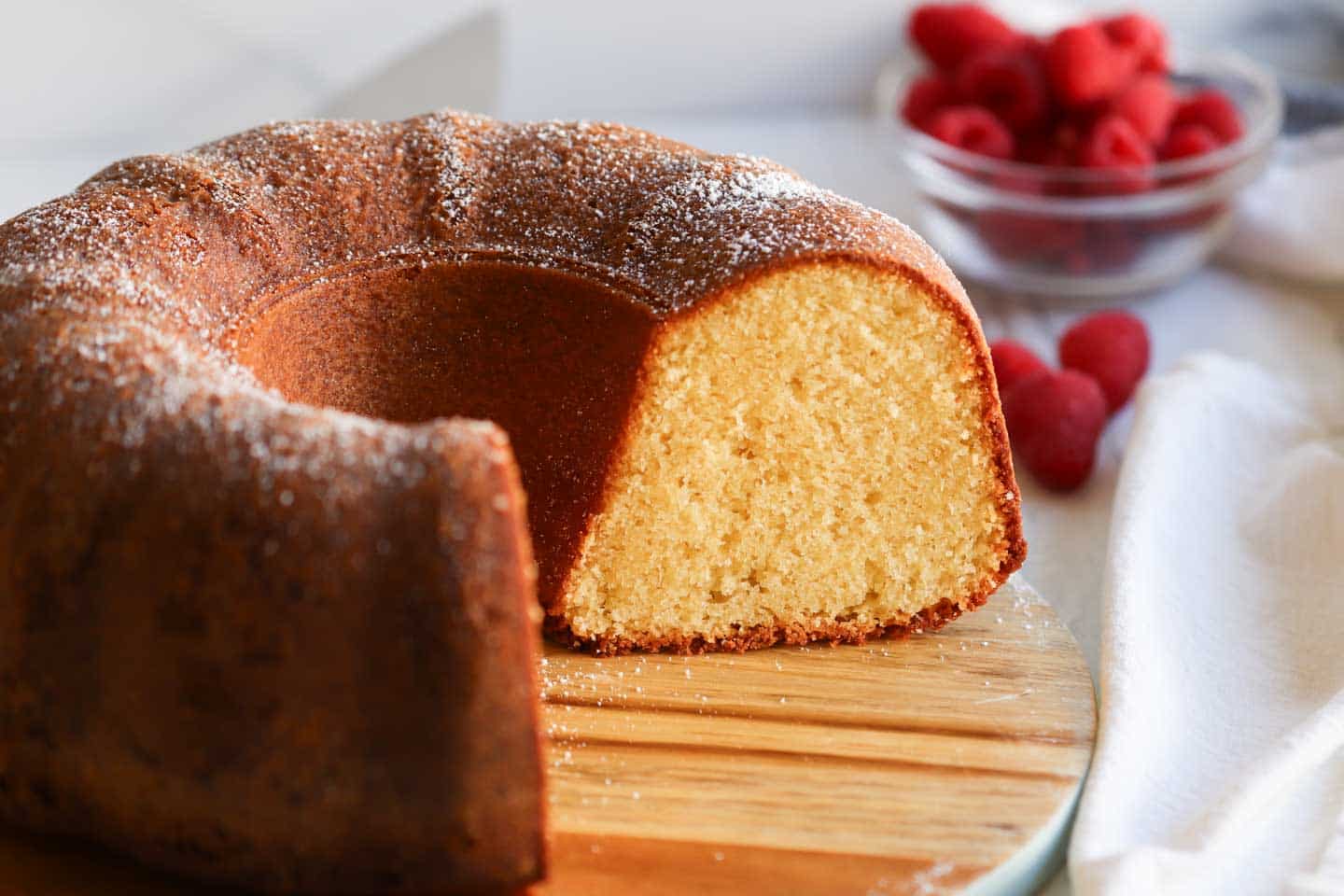 a bundt cake that's been cut with raspberries in the background